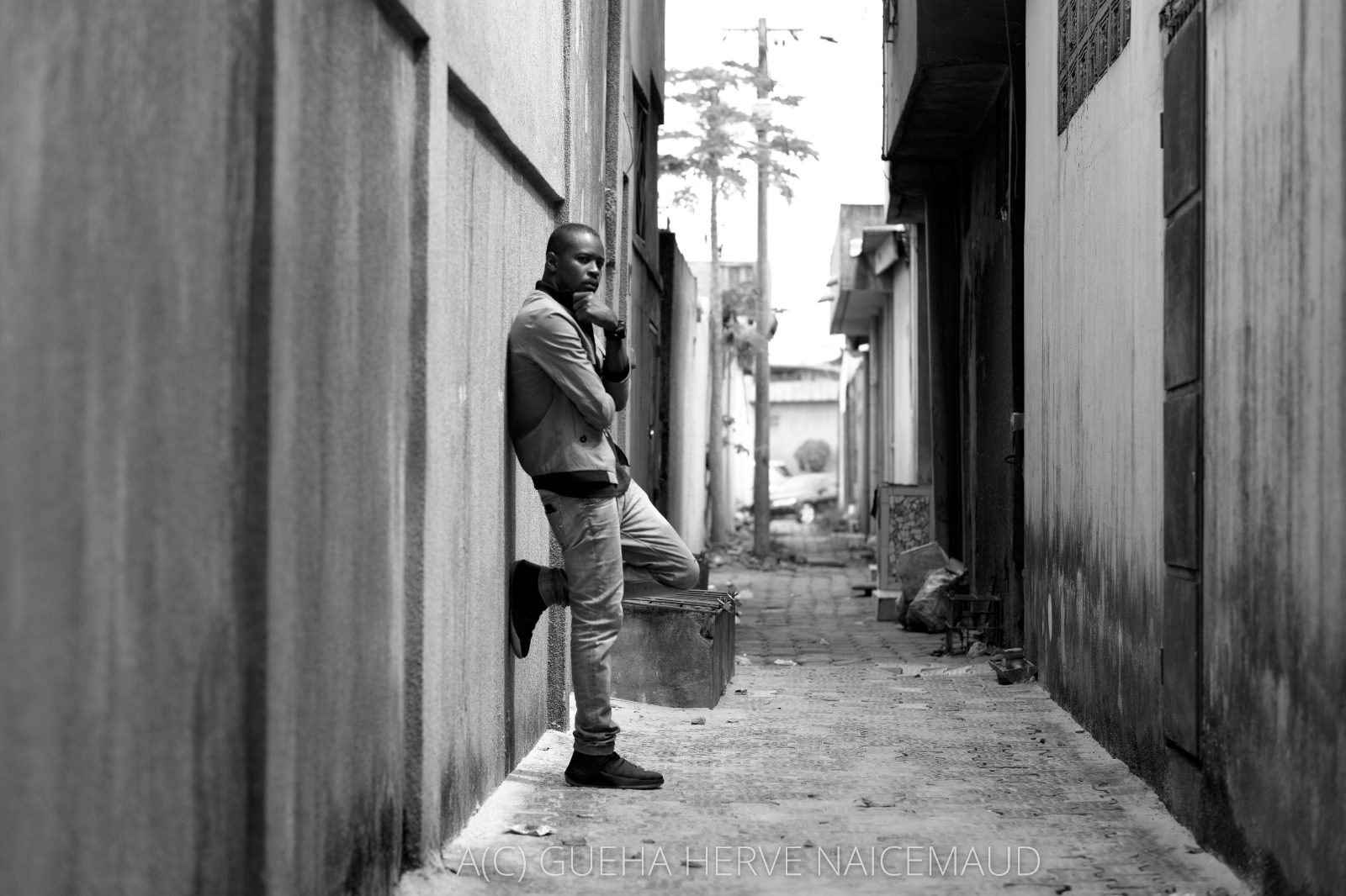 Despy adossé au mur d'une ruelle d'Abidjan, noir et blanc
